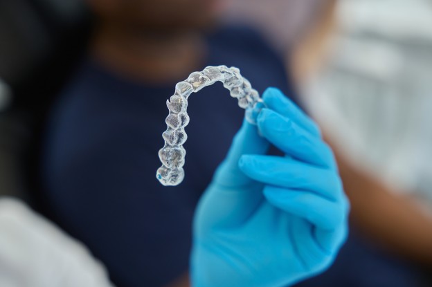 Dental professional holding a clear aligner tray during an Invisalign in Katy consultation